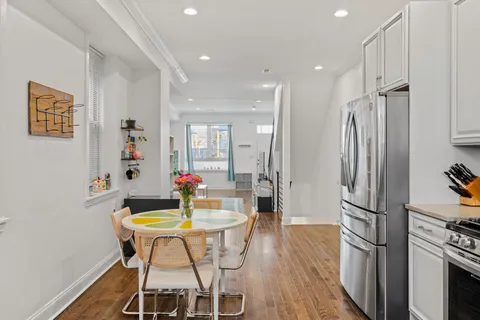 a kitchen with stainless steel appliances a dining table chairs refrigerator and stove