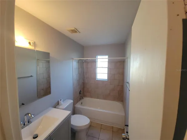 a bathroom with a bathtub shower sink vanity mirror and toilet