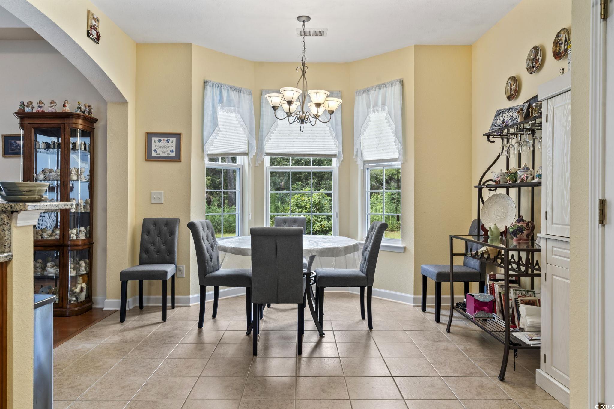 2356 Seneca Ridge Drive Myrtle Beach, SC 29579 - Photo 11 of 39 Dining area with light tile patterned floors, arched walkways, and a chandelier