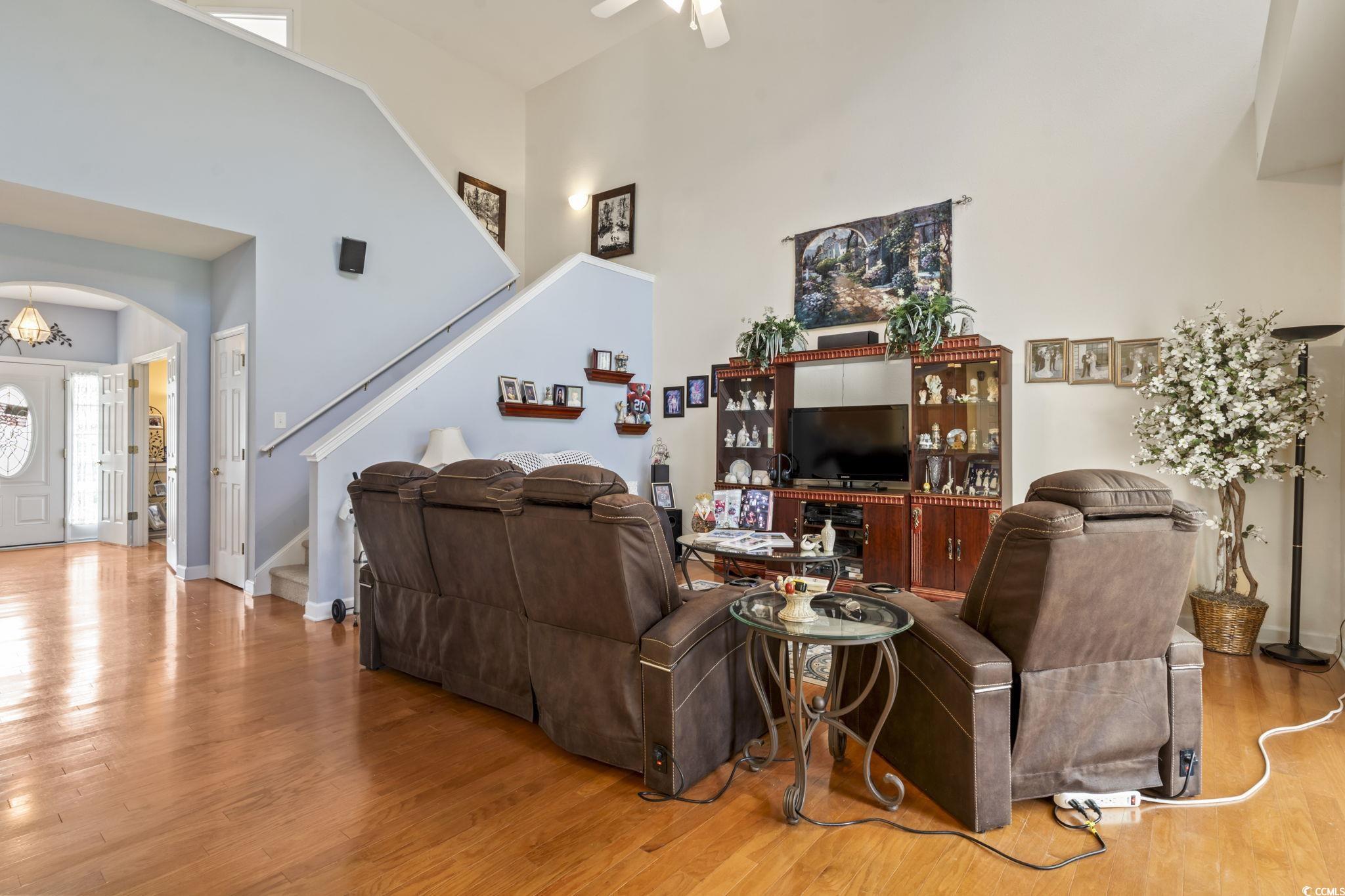 2356 Seneca Ridge Drive Myrtle Beach, SC 29579 - Photo 14 of 39 Living area with wood finished floors, a towering ceiling, stairs, a chandelier, and a ceiling fan