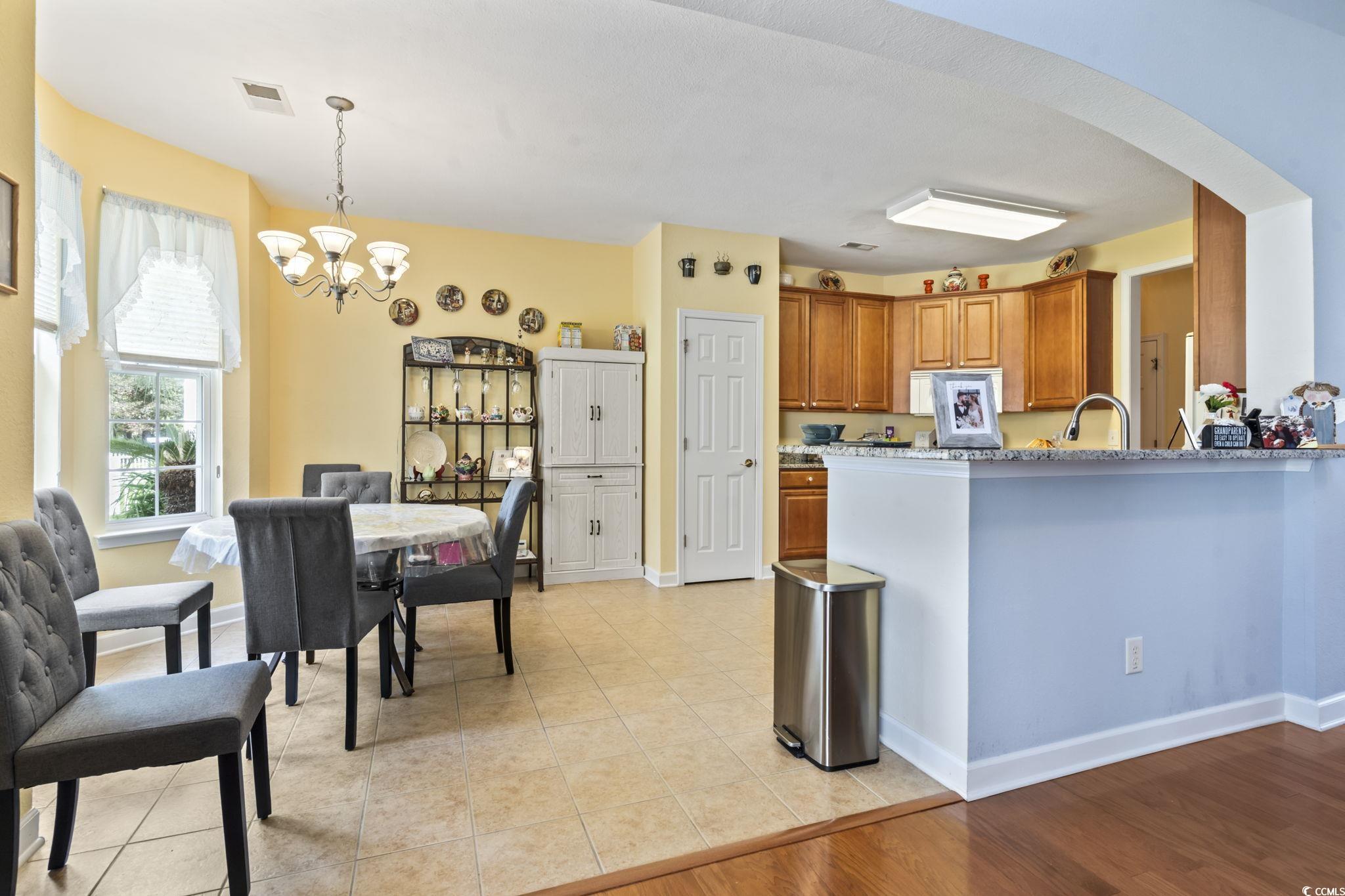 2356 Seneca Ridge Drive Myrtle Beach, SC 29579 - Photo 10 of 39 Kitchen featuring pendant lighting, brown cabinetry, arched walkways, light tile patterned floors, and a chandelier