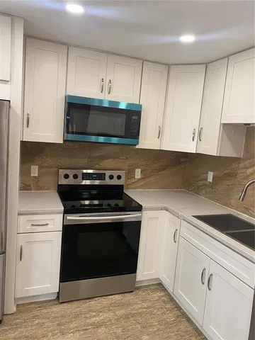 a kitchen with granite countertop white cabinets and white appliances