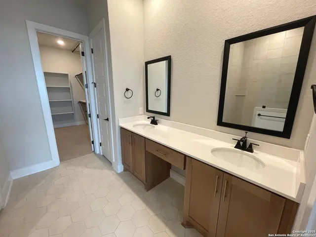 a bathroom with double vanity and a mirror