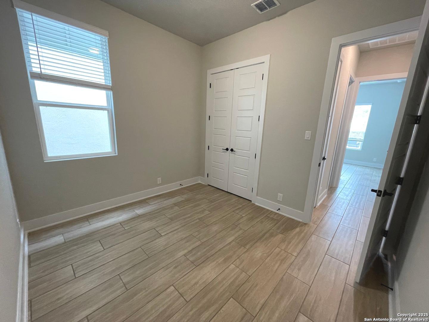 20675 Huebner Road, Unit 525 San Antonio, TX 78258 - Photo 16 of 19 an empty room with wooden floor and windows