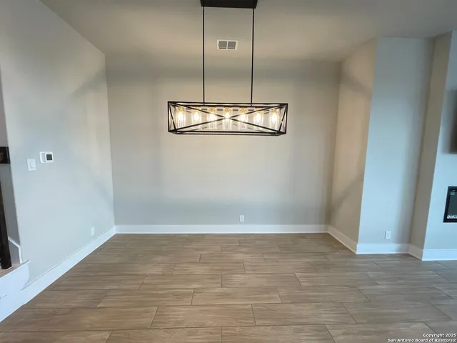 a view of a room with a hanging light and kitchen view