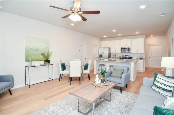 a kitchen with stainless steel appliances granite countertop a sink a stove a refrigerator and a dining table with wooden floor