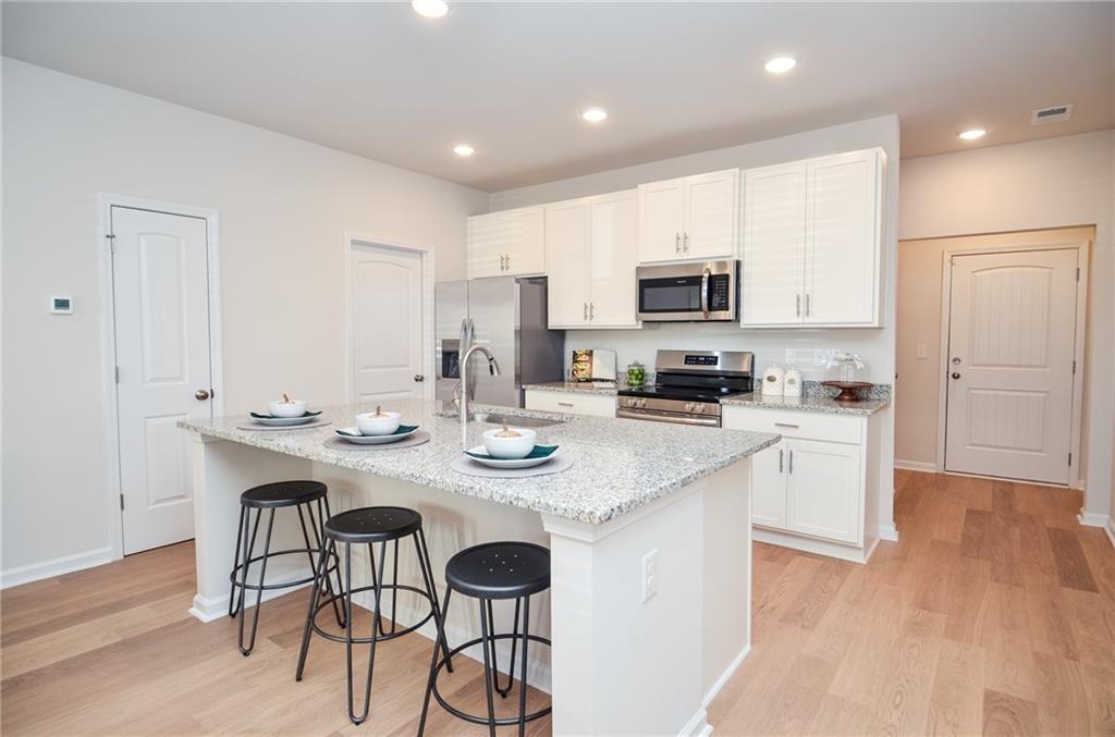 4551 High Rdg Court Sugar Hill, GA 30518 - Photo 15 of 40 a kitchen with stainless steel appliances granite countertop a sink a stove a refrigerator and a dining table with wooden floor