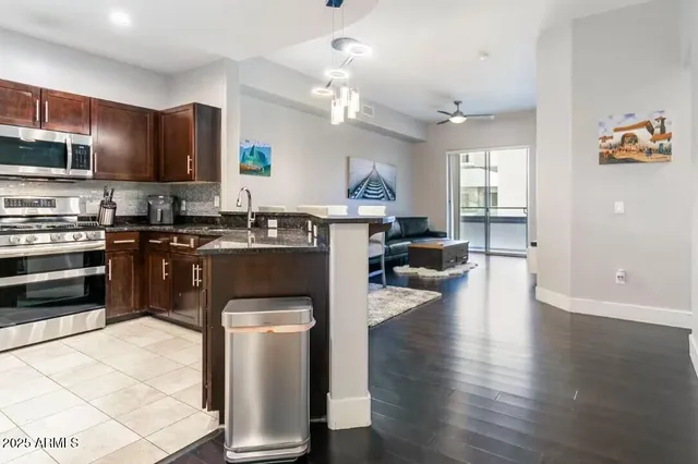 a kitchen with stainless steel appliances granite countertop a stove top oven a sink dishwasher a dining table and chairs with wooden floor