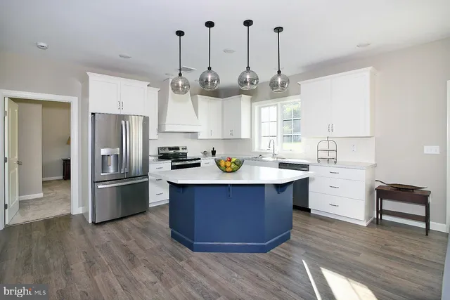 a kitchen with stainless steel appliances granite countertop a sink a stove a refrigerator and island with wooden floor