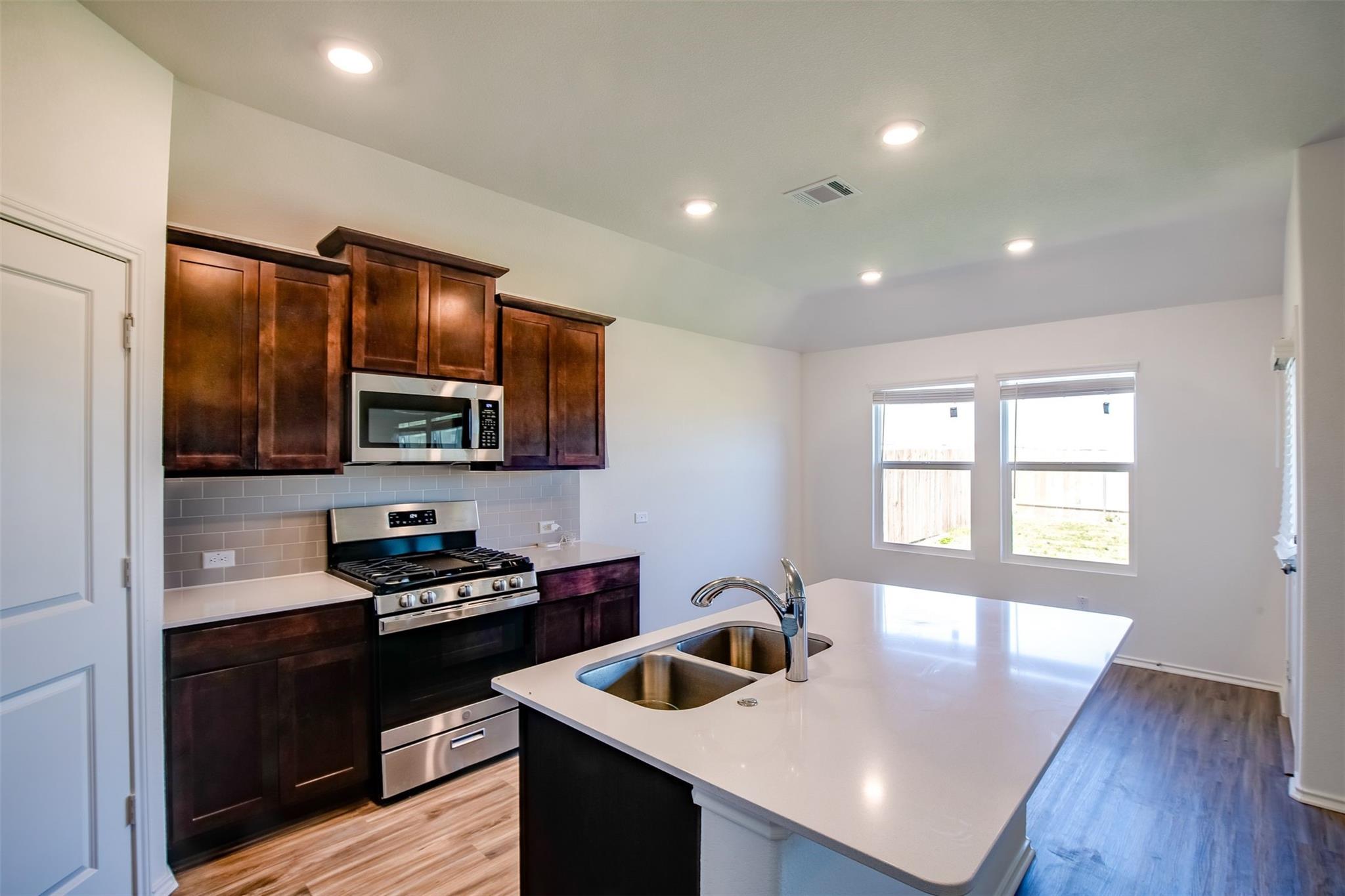 614 Milliner Loop Hutto, TX 78634 - Photo 20 of 25 A well-equipped kitchen features a central island, rich cabinetry, and a modern gas range.