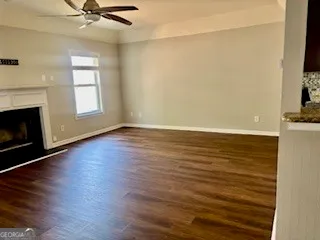 an empty room with wooden floor fireplace and windows