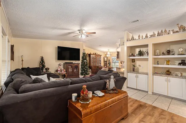 a living room with furniture a flat screen tv and kitchen view