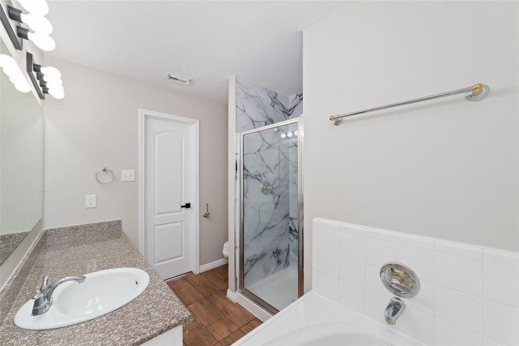 4007 Starbridge Pointe Lane Katy, TX 77449 - Photo 20 of 30 a bathroom with a granite countertop sink a toilet and shower