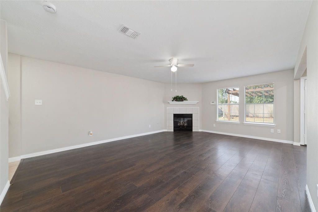 4007 Starbridge Pointe Lane Katy, TX 77449 - Photo 6 of 30 an empty room with wooden floor fireplace and windows