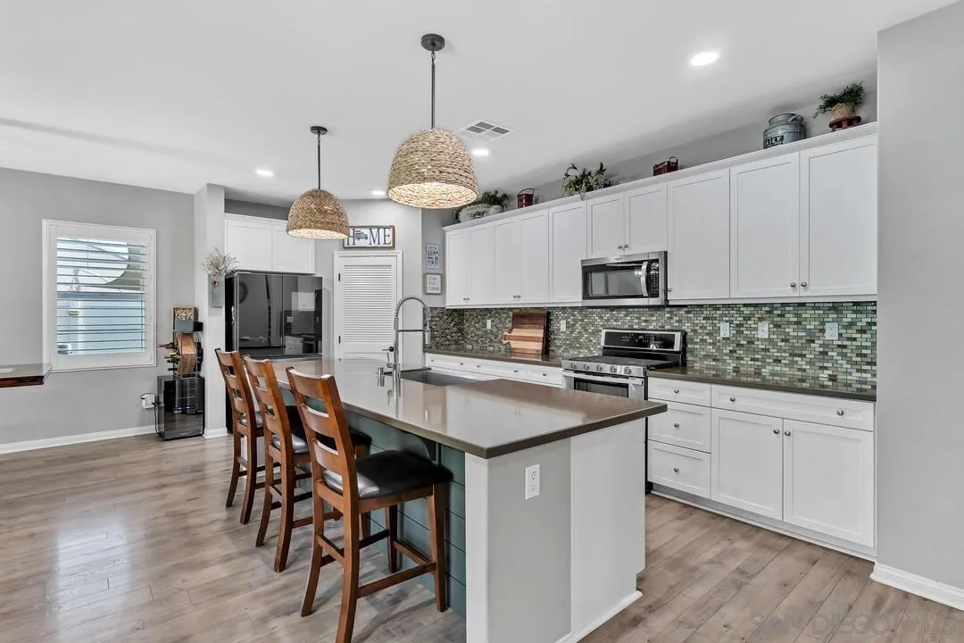 10700 Spring Creek Drive Santee, CA 92071 - Photo 14 of 74 a kitchen with stainless steel appliances kitchen island granite countertop a sink a stove a dining table and chairs