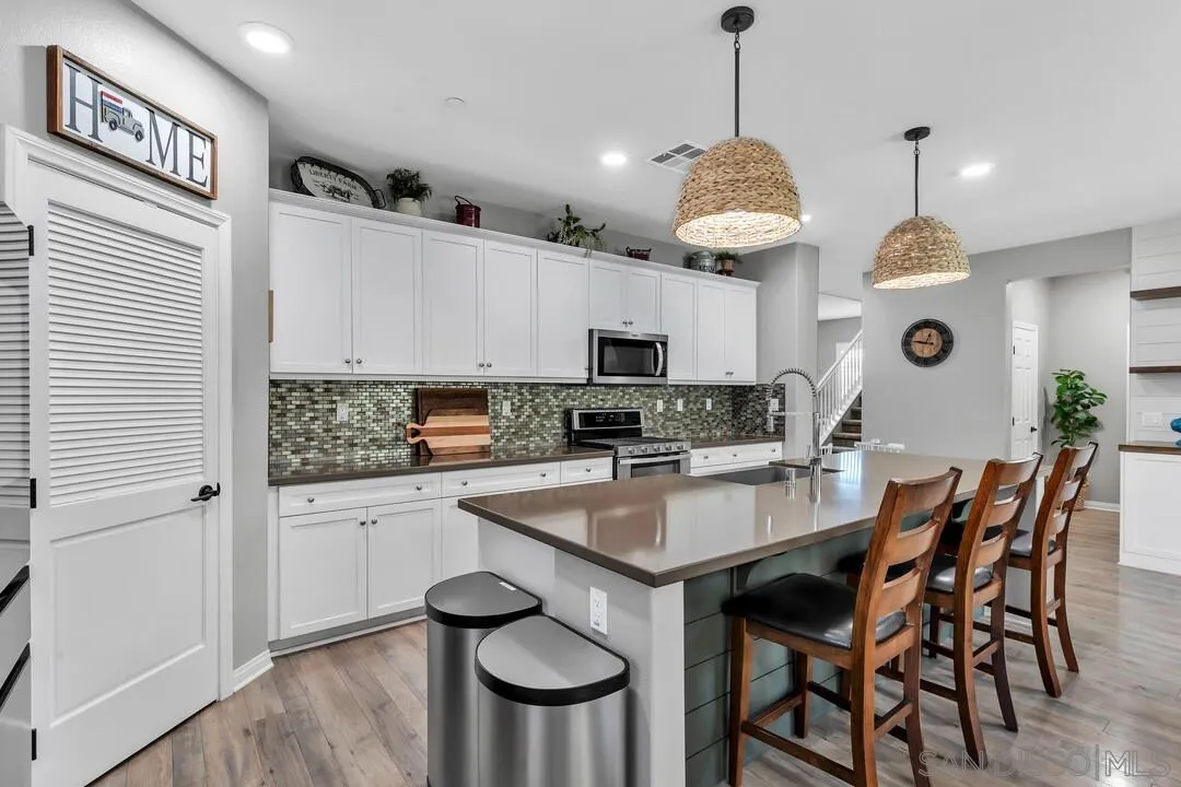 10700 Spring Creek Drive Santee, CA 92071 - Photo 15 of 74 a kitchen with stainless steel appliances granite countertop a stove a sink dishwasher a dining table and chairs with wooden floor