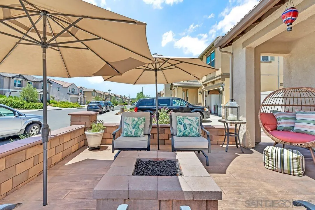 10700 Spring Creek Drive Santee, CA 92071 - Photo 7 of 74 a view of a patio with a dining table and chairs under an umbrella with a small garden