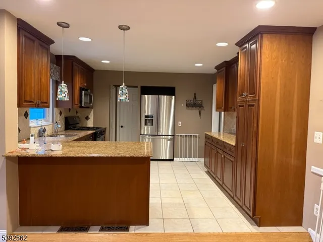 a kitchen with stainless steel appliances kitchen island granite countertop a refrigerator and a sink