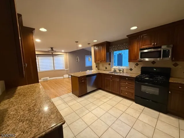 a kitchen with stainless steel appliances kitchen island granite countertop a stove a sink and a refrigerator