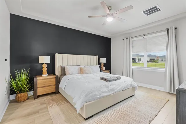 a bedroom with a large bed and a chandelier fan