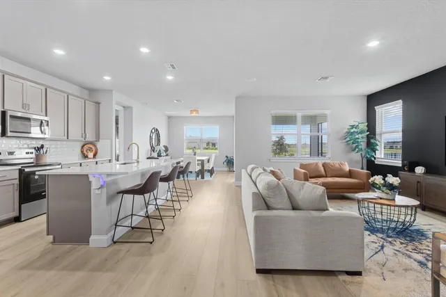 a living room with furniture a wooden floor and a view of kitchen