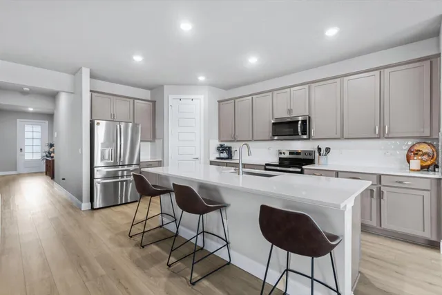 a kitchen with granite countertop a stove a sink dishwasher and a refrigerator with wooden floor