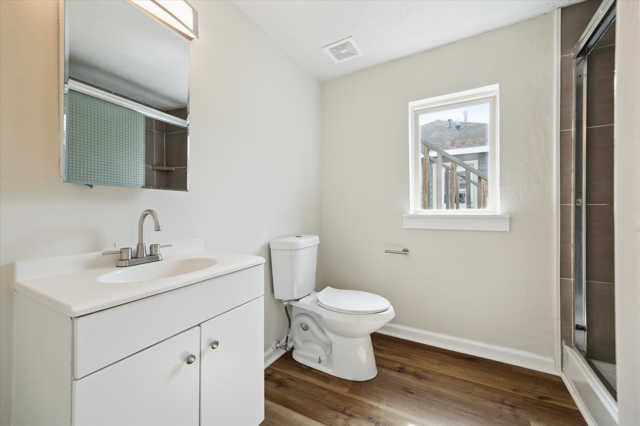 2802 Hardy Street, Unit C Houston, TX 77009 - Photo 10 of 18 a bathroom with a toilet a sink a mirror and a window