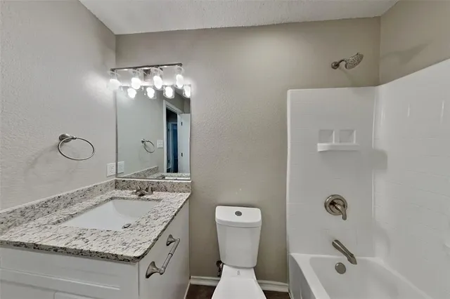 a bathroom with a granite countertop sink a toilet and shower