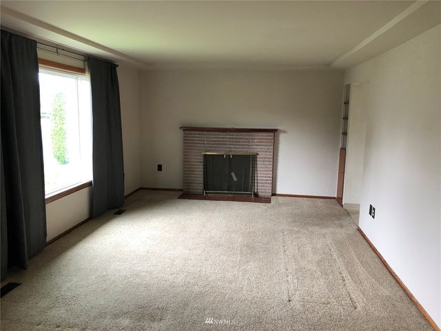 an empty room with a fireplace and windows