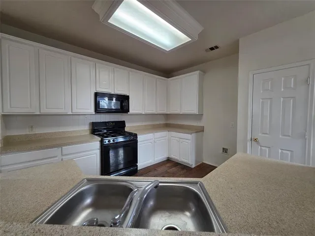 a kitchen that has a sink and white cabinets