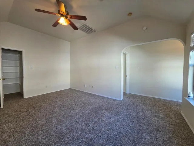 an empty room with windows and ceiling fan
