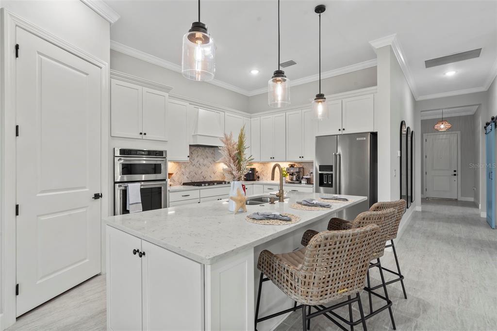 14560 Eagle Branch Drive Nokomis, FL 34275 - Photo 24 of 65 a kitchen with stainless steel appliances a dining table chairs refrigerator and microwave
