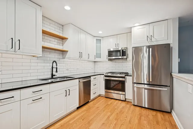 a kitchen with cabinets stainless steel appliances a sink and a window