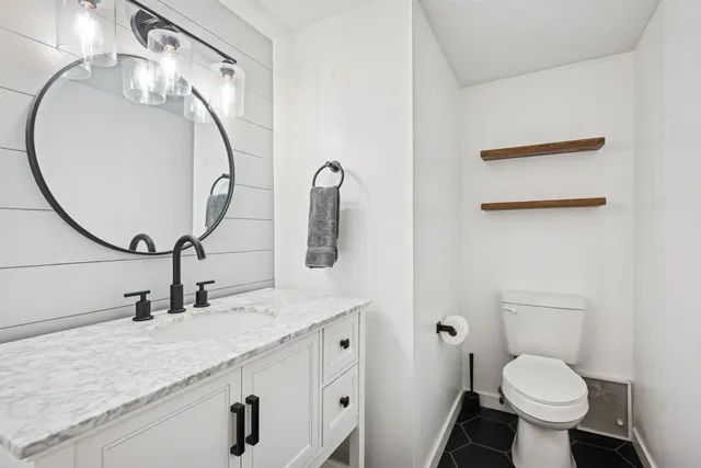 a bathroom with a granite countertop toilet sink and mirror