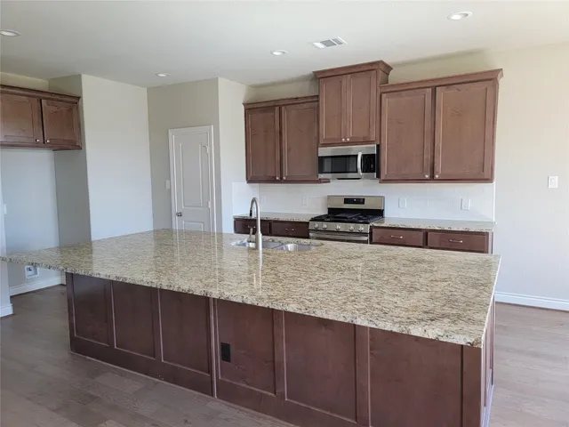 a kitchen with kitchen island granite countertop a sink stove and cabinets