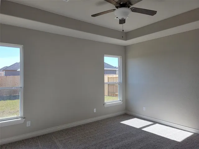 an empty room with windows and ceiling fan