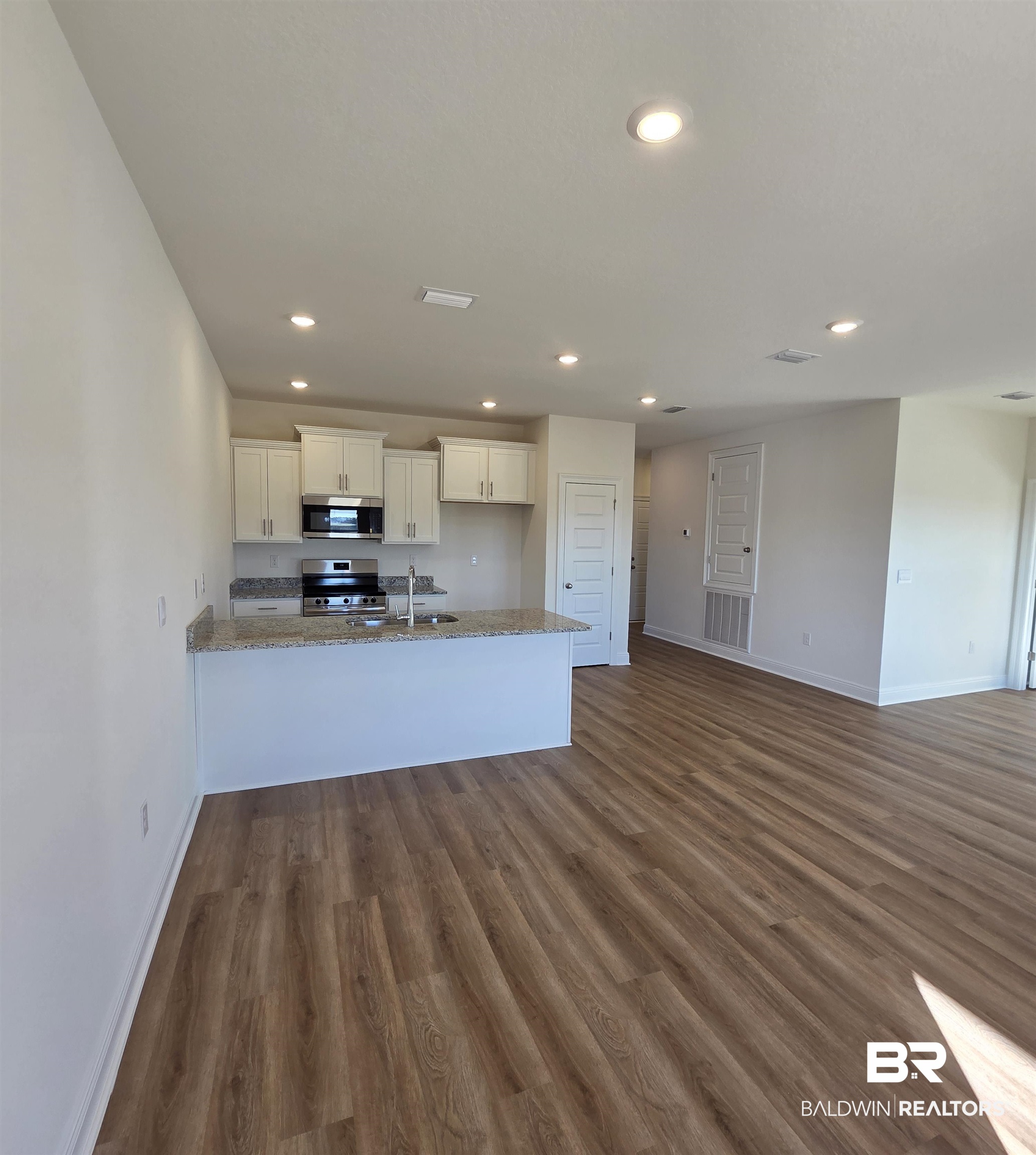 28084 Hallow Trail Elberta, AL 36530 - Photo 6 of 21 Kitchen with white cabinetry, dark wood-style flooring, a peninsula, appliances with stainless steel finishes, and light stone counters