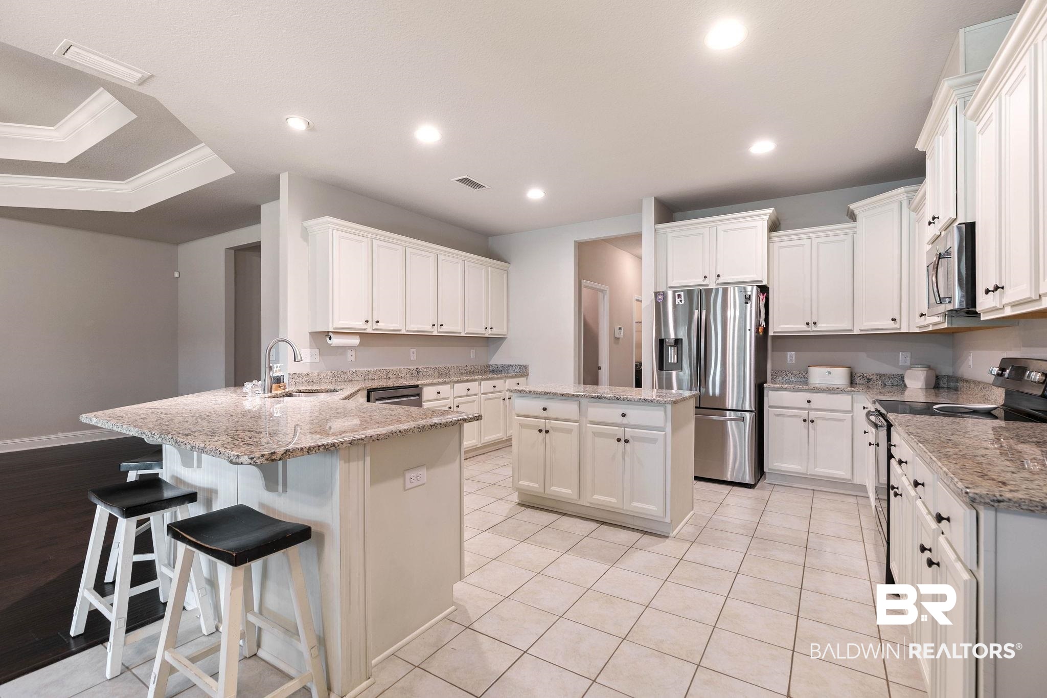12750 B Jenkins Pit Road Daphne, AL 36527 - Photo 19 of 89 Kitchen featuring a peninsula, stainless steel appliances, a breakfast bar, a center island, and white cabinetry