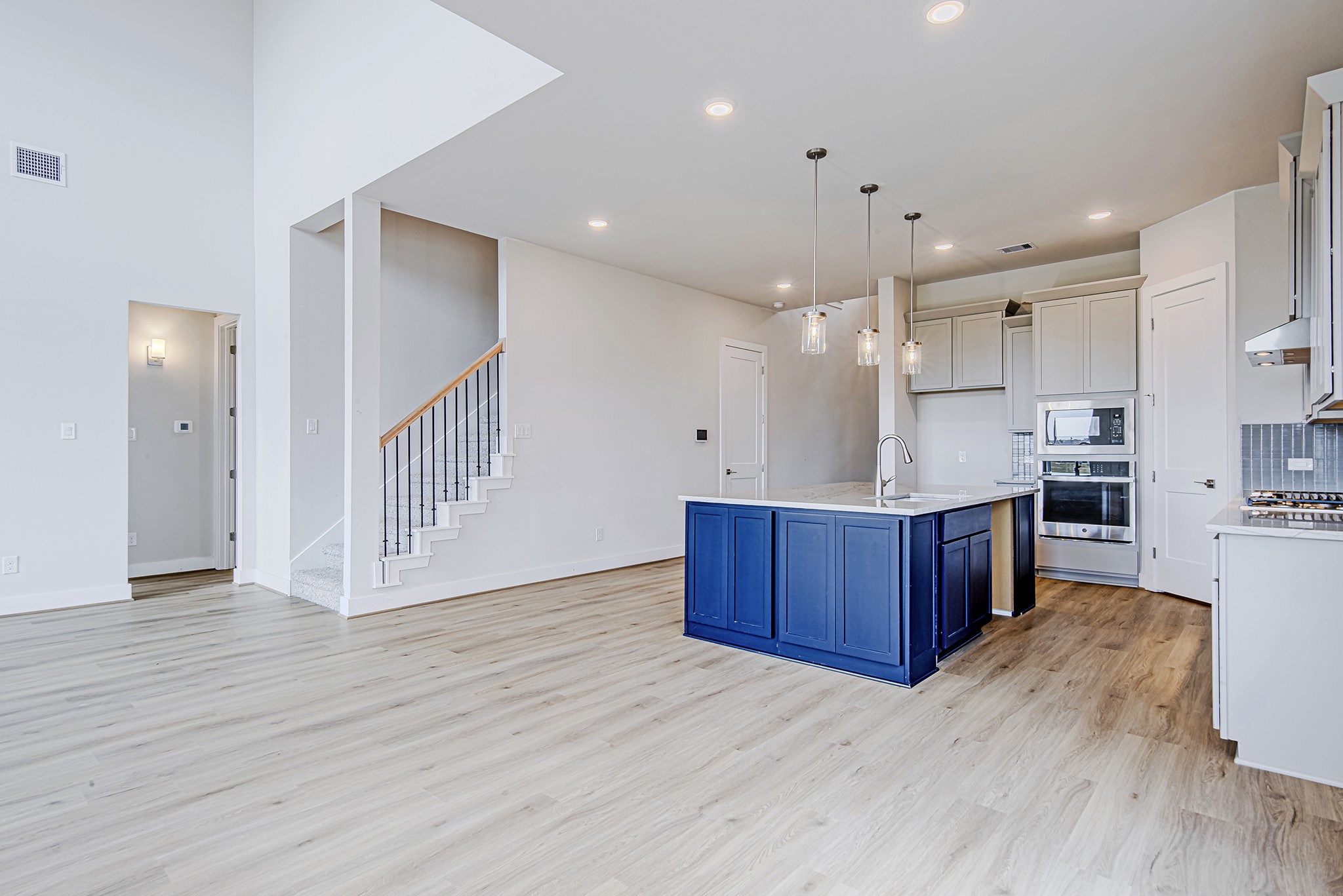181 Peninsula Point Drive Montgomery, TX 77356 - Photo 13 of 44 The kitchen stands out with a bold navy island, quartz countertops, and sleek pendant lighting. Soft cabinetry tones and stainless appliances create a polished, modern feel, while the adjacent staircase adds a stylish architectural detail.