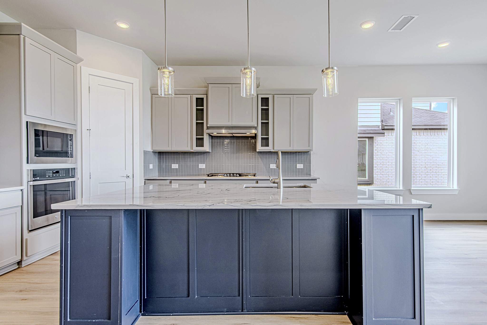 181 Peninsula Point Drive Montgomery, TX 77356 - Photo 10 of 44 The expansive island takes center stage with its navy cabinetry, marble-style quartz counters, and trio of pendant lights that lend a modern, elegant touch.