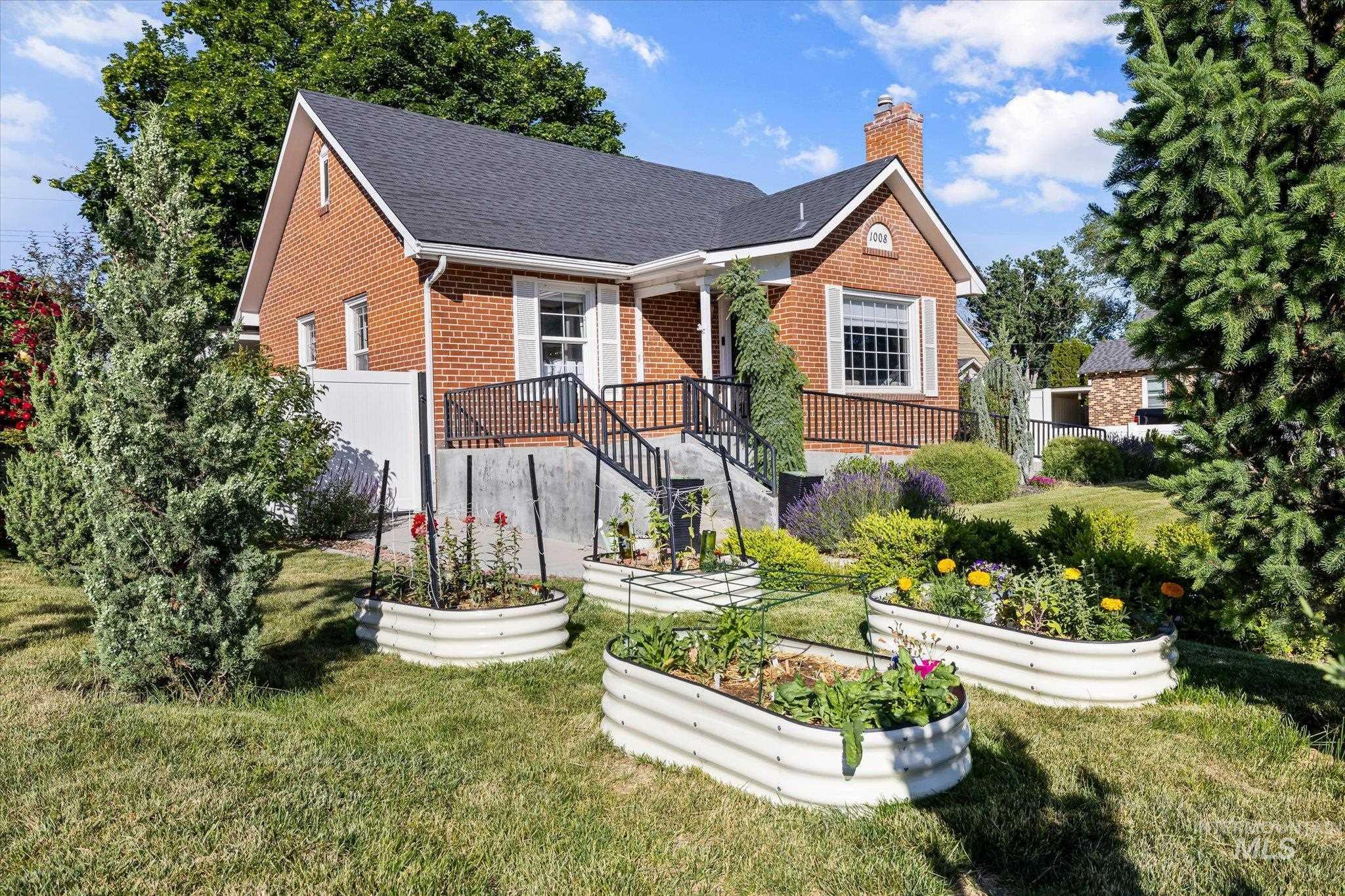 1008 Fillmore Street Caldwell, ID 83605 - Photo 1 of 50 View of front of property featuring brick siding, a vegetable garden, a chimney, and a shingled roof