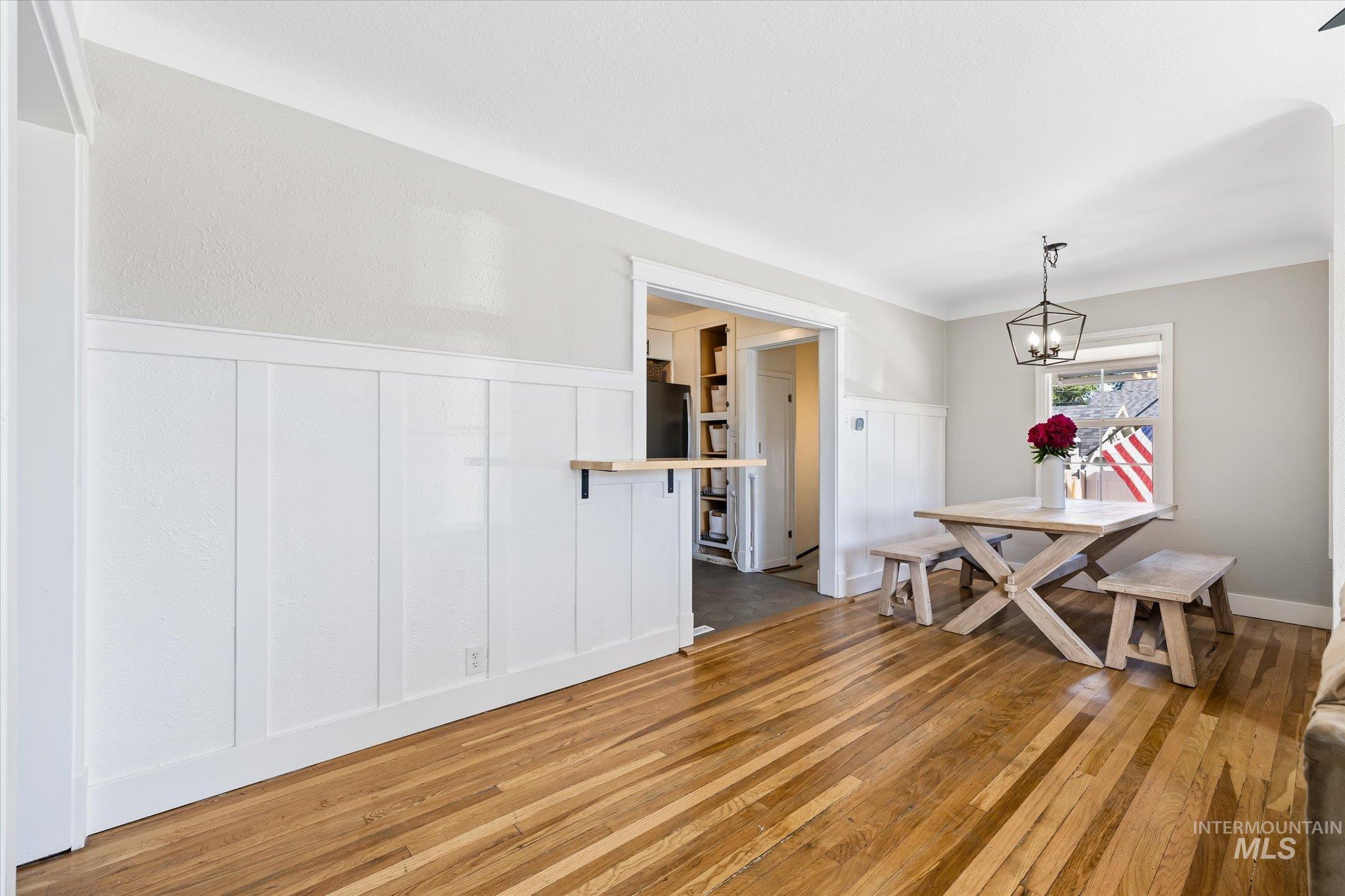 1008 Fillmore Street Caldwell, ID 83605 - Photo 39 of 50 Dining space with light wood-style flooring, a wainscoted wall, a decorative wall, and a chandelier