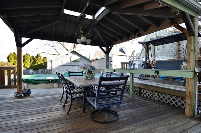 a patio with wooden floor a yard a table and chairs