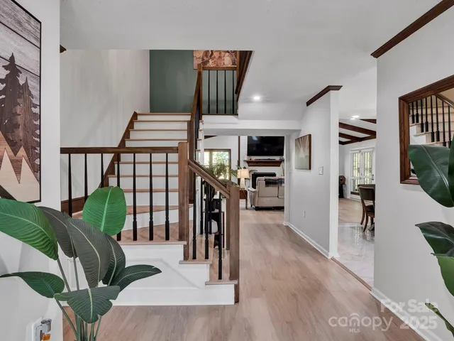a livingroom with furniture a rug potted plants and wooden floor