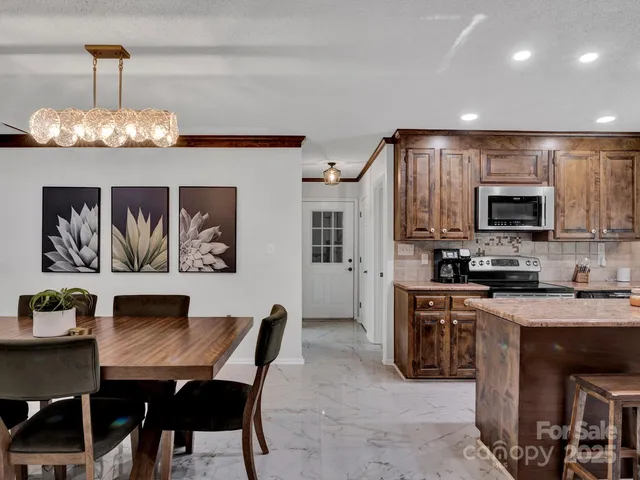 a view of kitchen with microwave stove refrigerator dining table and chairs