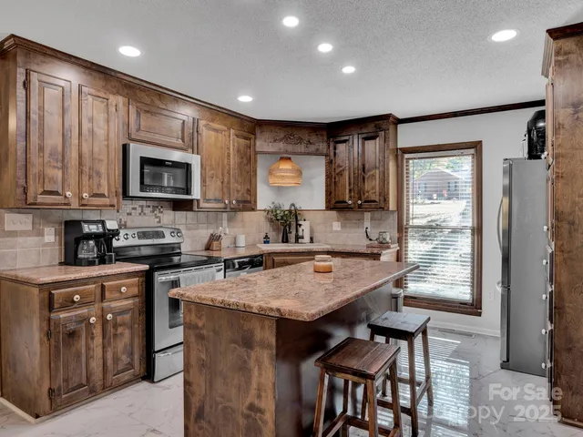 a kitchen with kitchen island granite countertop wooden cabinets a stove a sink and a refrigerator