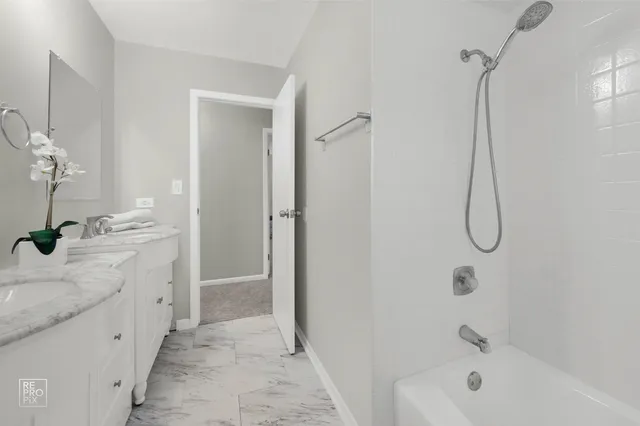 a spacious bathroom with a granite countertop sink a mirror and a bathtub