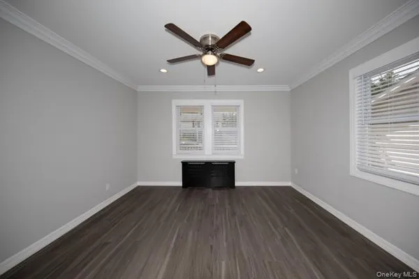 an empty room with wooden floor a ceiling fan and windows