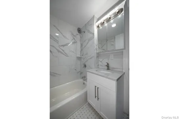 a bathroom with a granite countertop bathtub shower sink and mirror