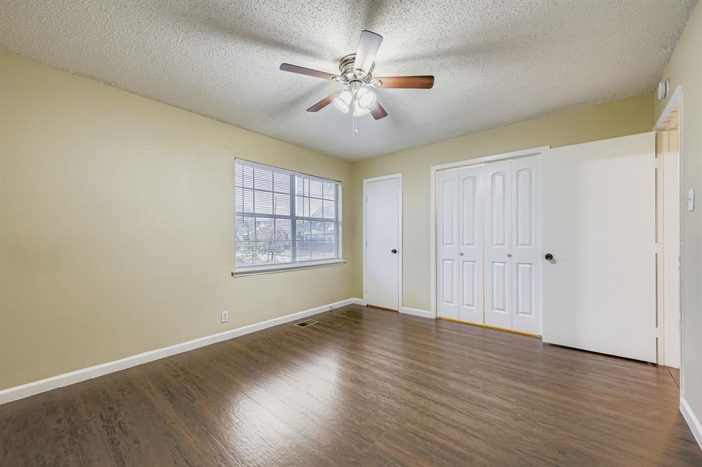 214 Austin Street Grapevine, TX 76051 - Photo 14 of 28 an empty room with wooden floor chandelier fan and windows